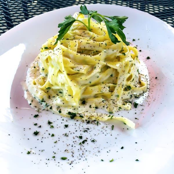 Franco's Italian Restaurant's creamy fettuccine alfredo pasta, garnished with fresh parsley and black pepper.