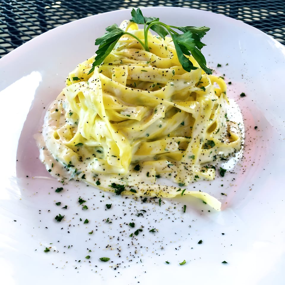 Franco's Italian Restaurant's creamy fettuccine alfredo pasta, garnished with fresh parsley and black pepper.